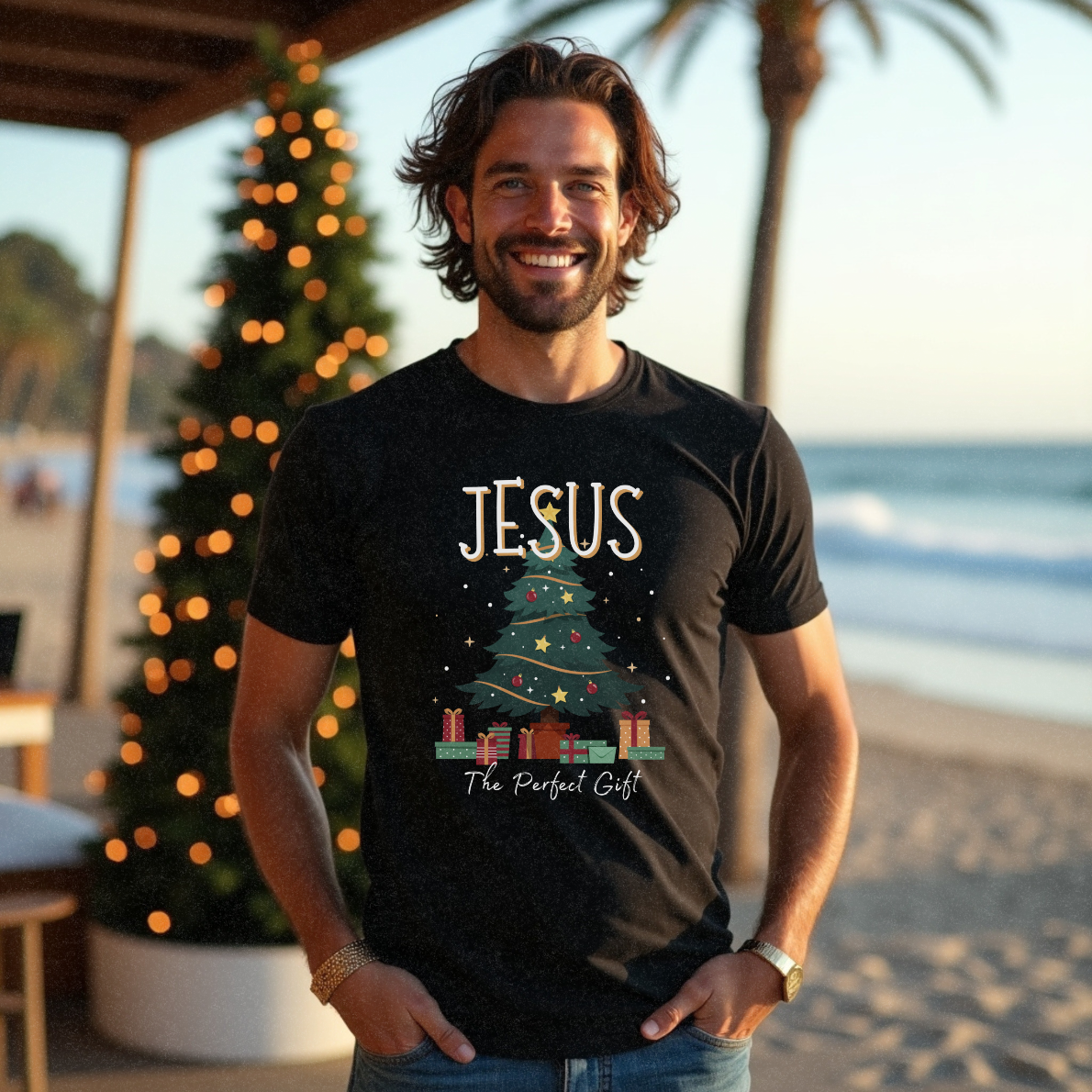 Male model standing at a cafe near the beach wearing a black Christmas t-shirt with the words 'Jesus The Perfect Gift' by Faith Looks Good