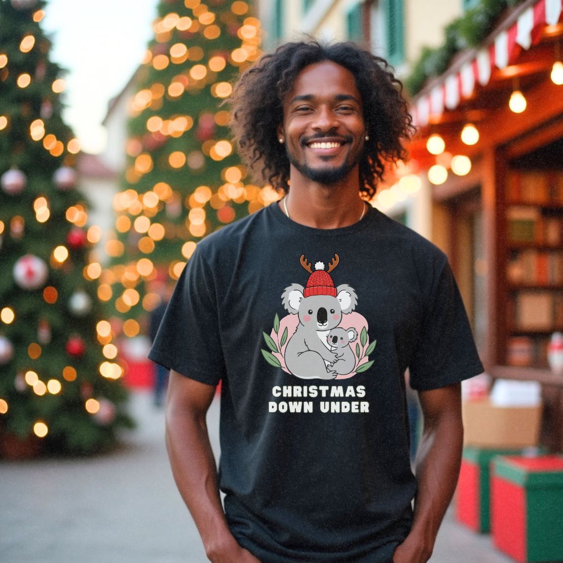 Young male model standing near a Christmas tree and some shops wearing a funny black Christmas t-shirt with koalas on it one with a red Christmas hat with antlers with 'Christmas Down Under' by Faith Looks Good