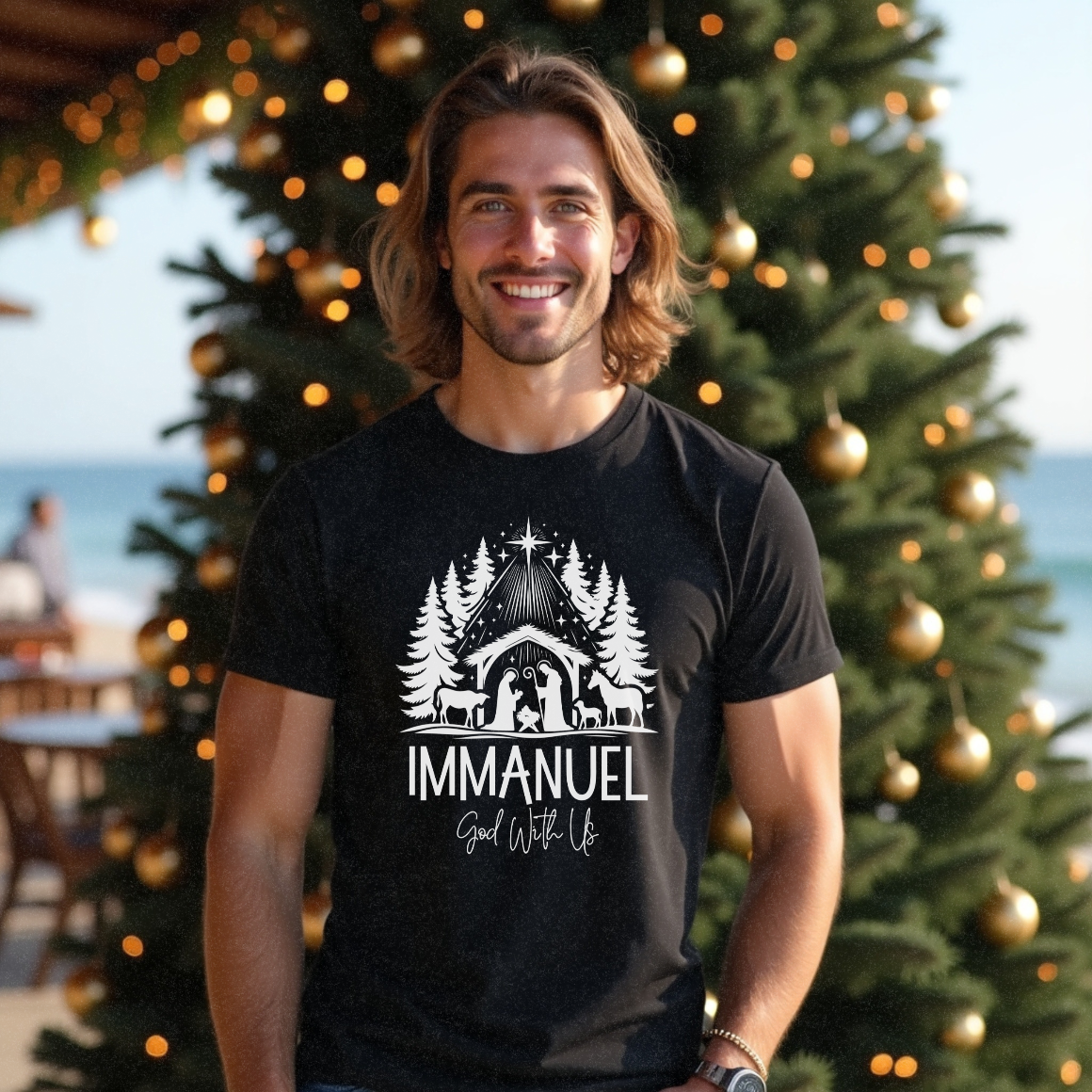 Male surfer in his 20s with short brown hair wearing a black Christmas t-shirt with a nativity scene in white text saying 'Immanuel God With Us' by Faith Looks Good