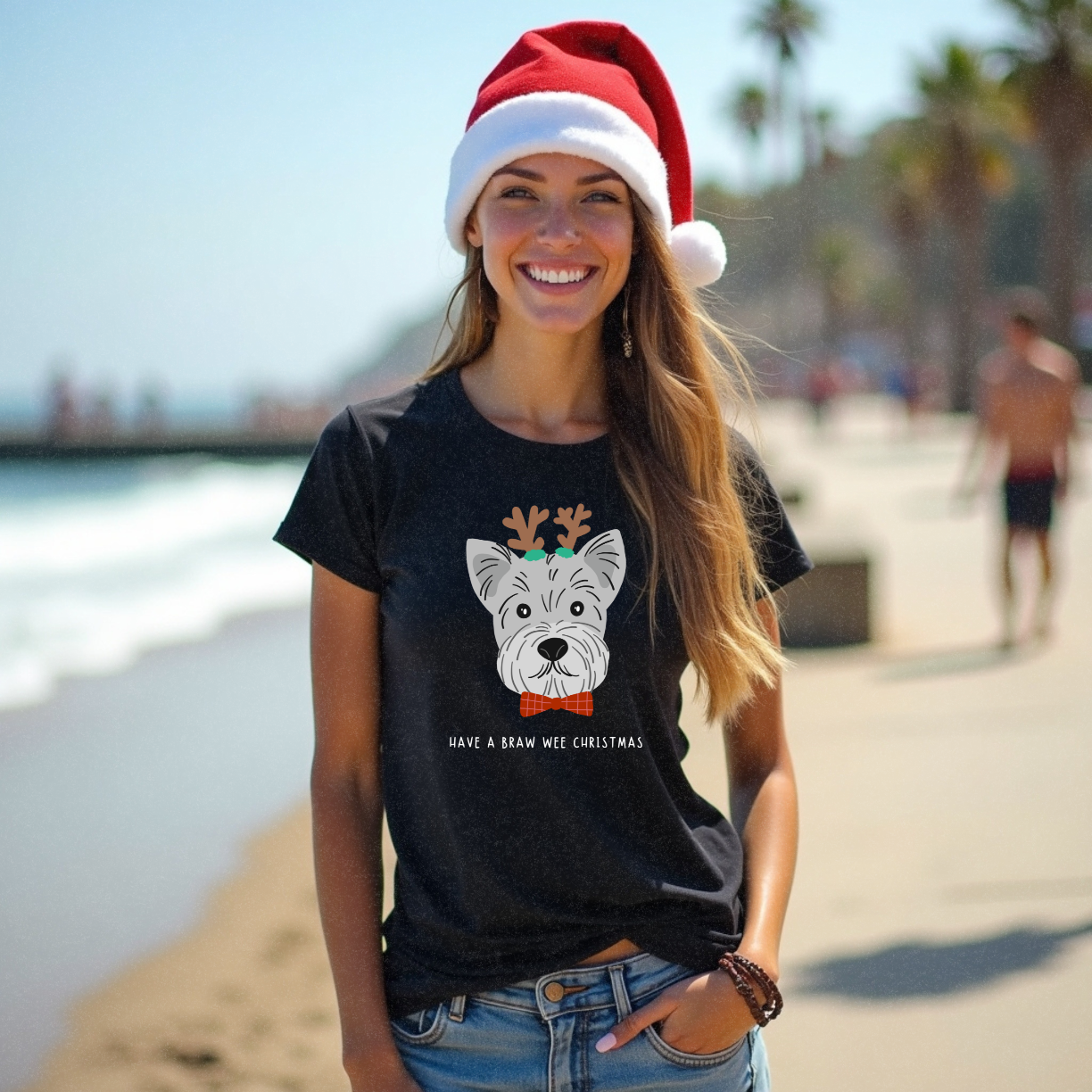Young model with long brown hair on the beach modelling a funny black Christmas t-shirt with a face of a Scotty dog wearing antlers with the words 'Have A Braw Wee Christmas' by Faith Looks Good
